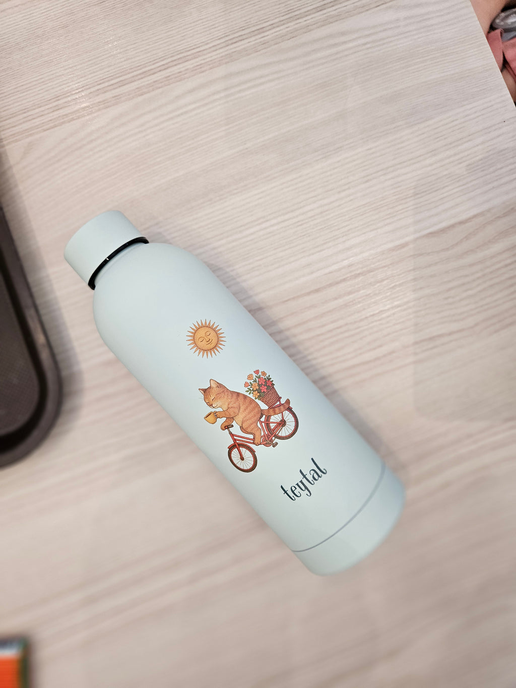 Termo blanco mate con diseño de gato en bicicleta y texto "enjoyful", capacidad 500 ml.