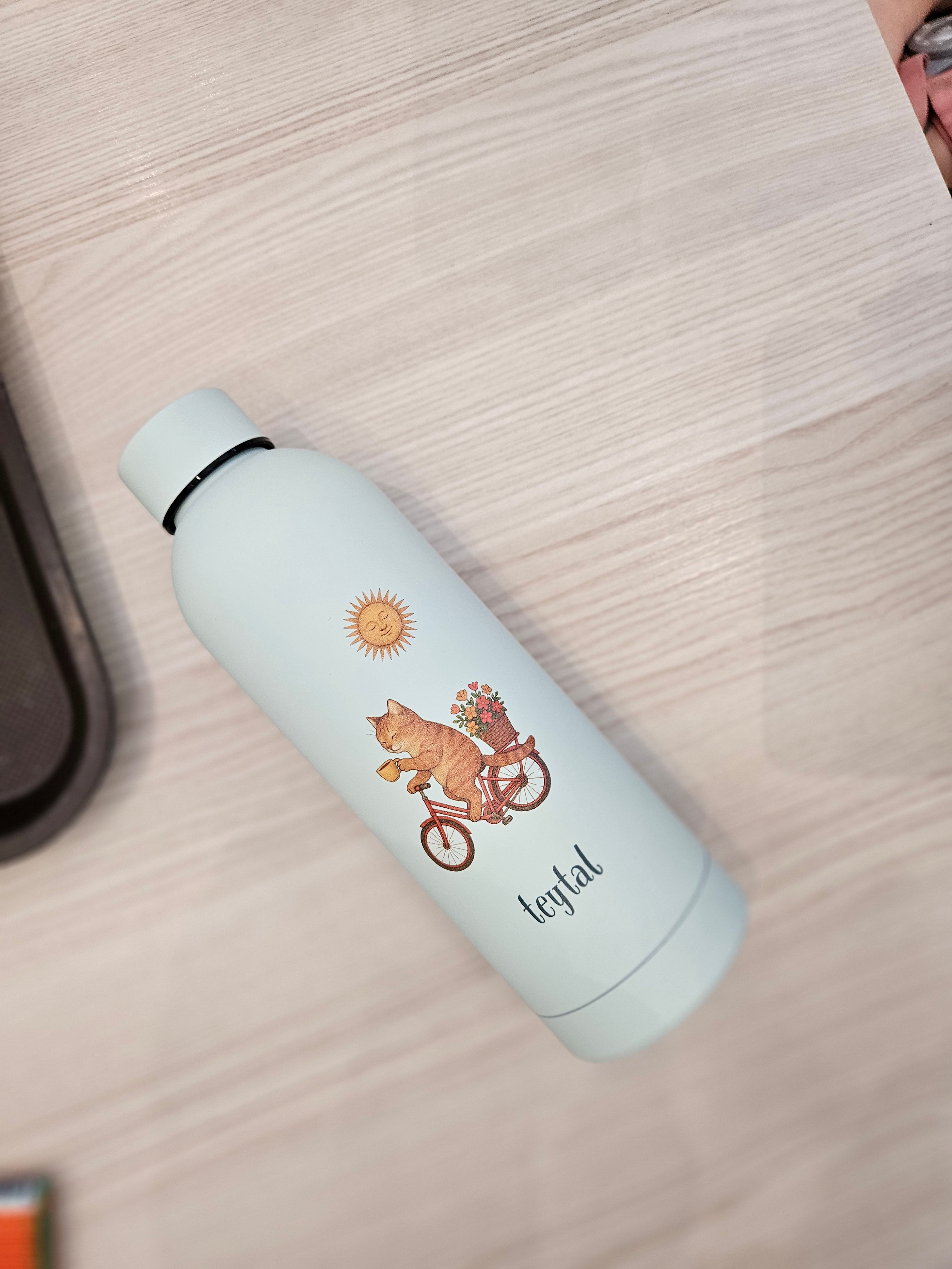 Termo blanco mate con diseño de gato en bicicleta y texto "enjoyful", capacidad 500 ml.