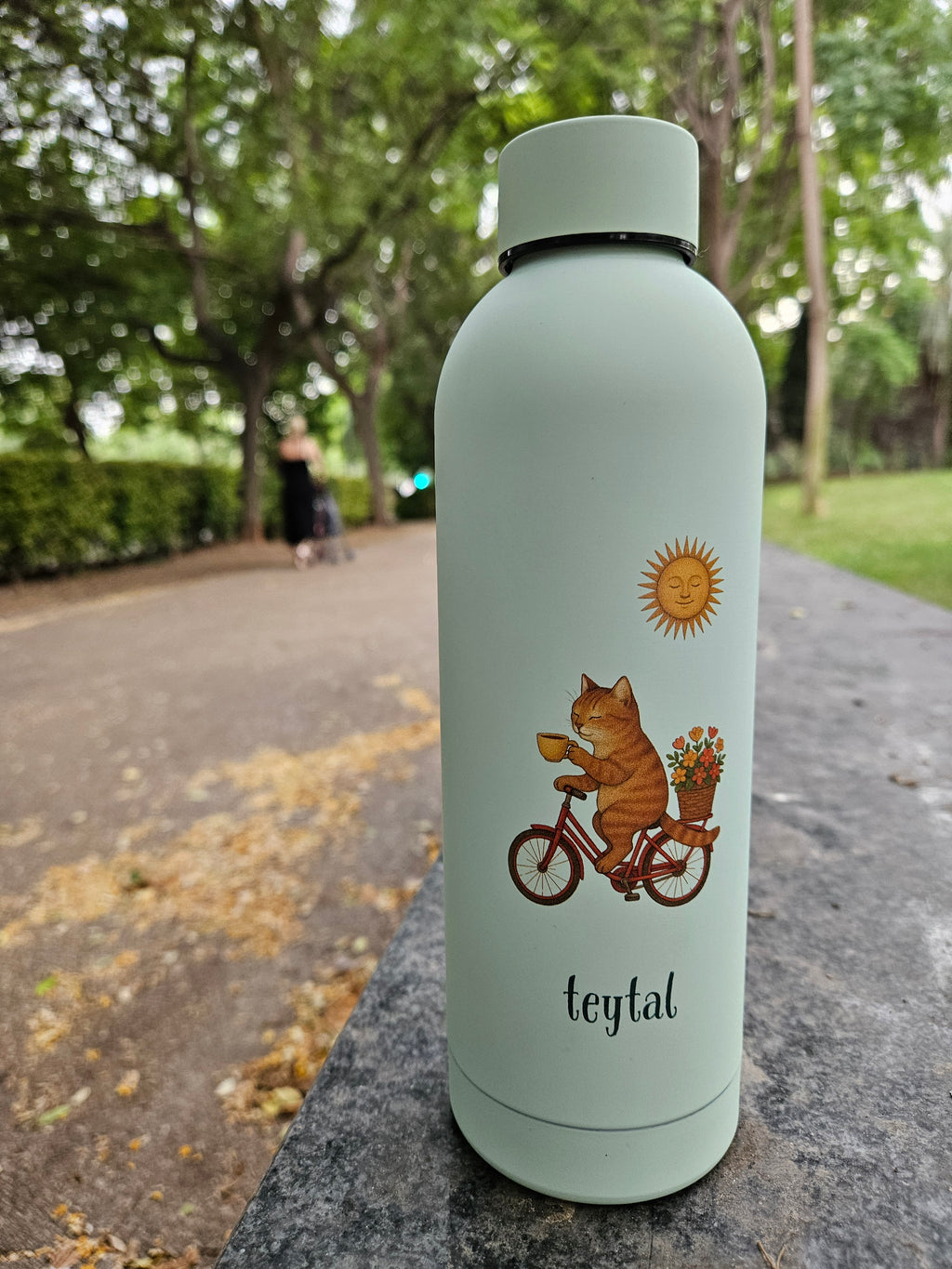 Termo celeste mate con diseño de gato en bicicleta y sol, tapa a rosca, capacidad 500 ml.