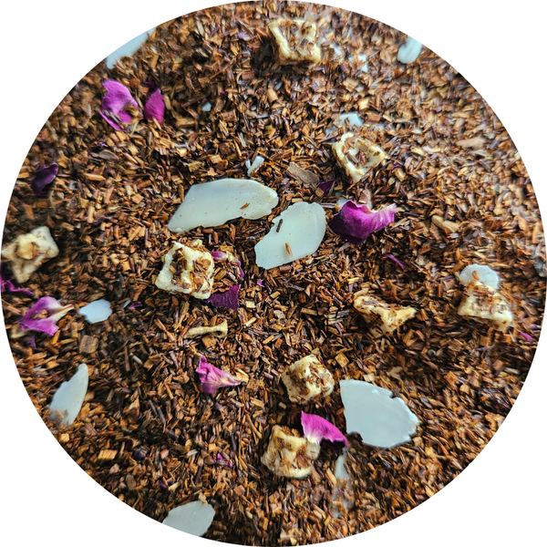Mezcla de rooibos con trozos de manzana, pétalos de rosa y almendra laminada rosa, en primer plano.