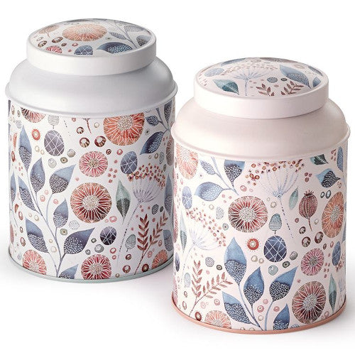 Latas metálicas decoradas con flores silvestres en tonos azules, rosas y naranjas, tapa blanca y rosa pastel.