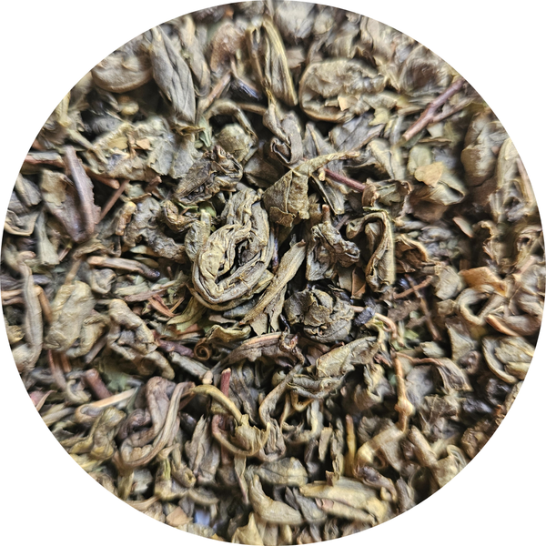Hojas secas de té verde Moruno en tonos verdes y marrones, pulverizadas y enrolladas.