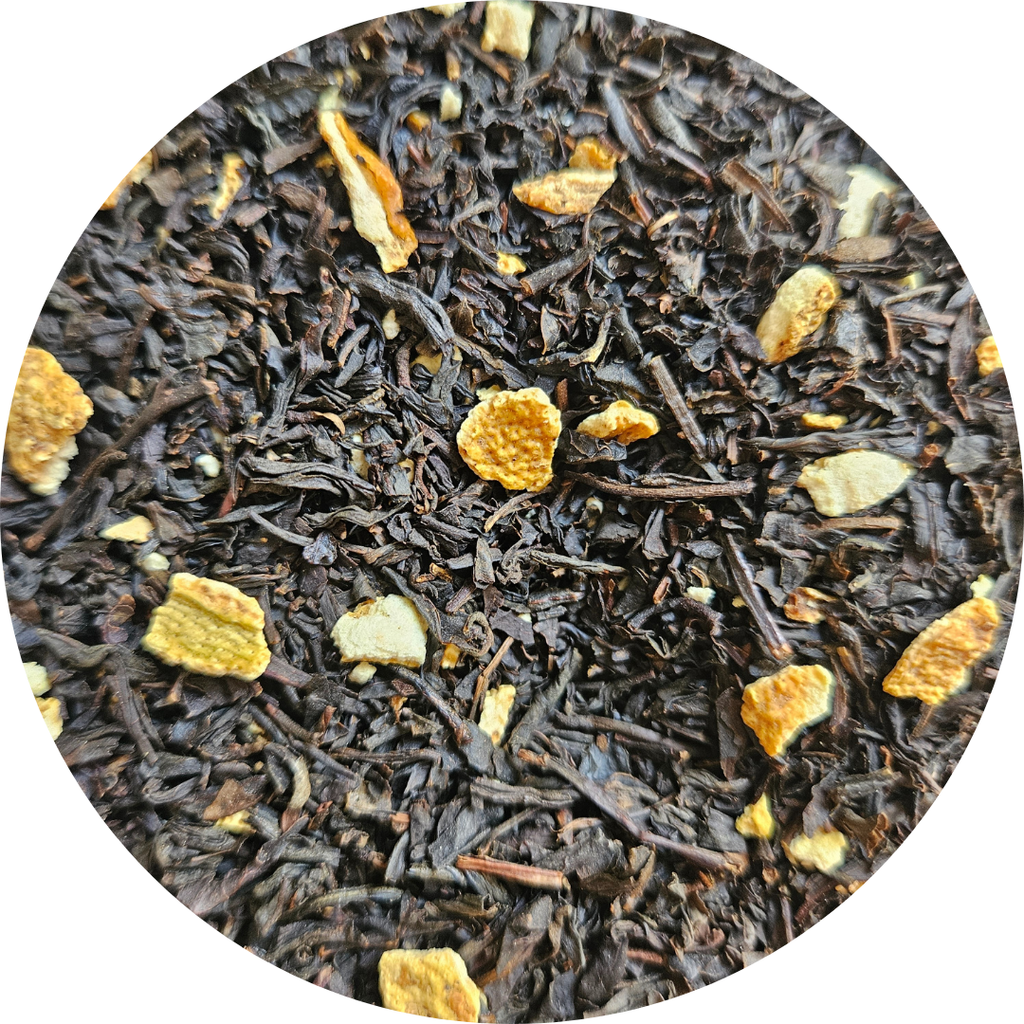 Hojas de té negro con trozos secos de naranja en primer plano.