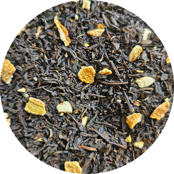 Hojas de té negro con trozos secos de naranja en primer plano.
