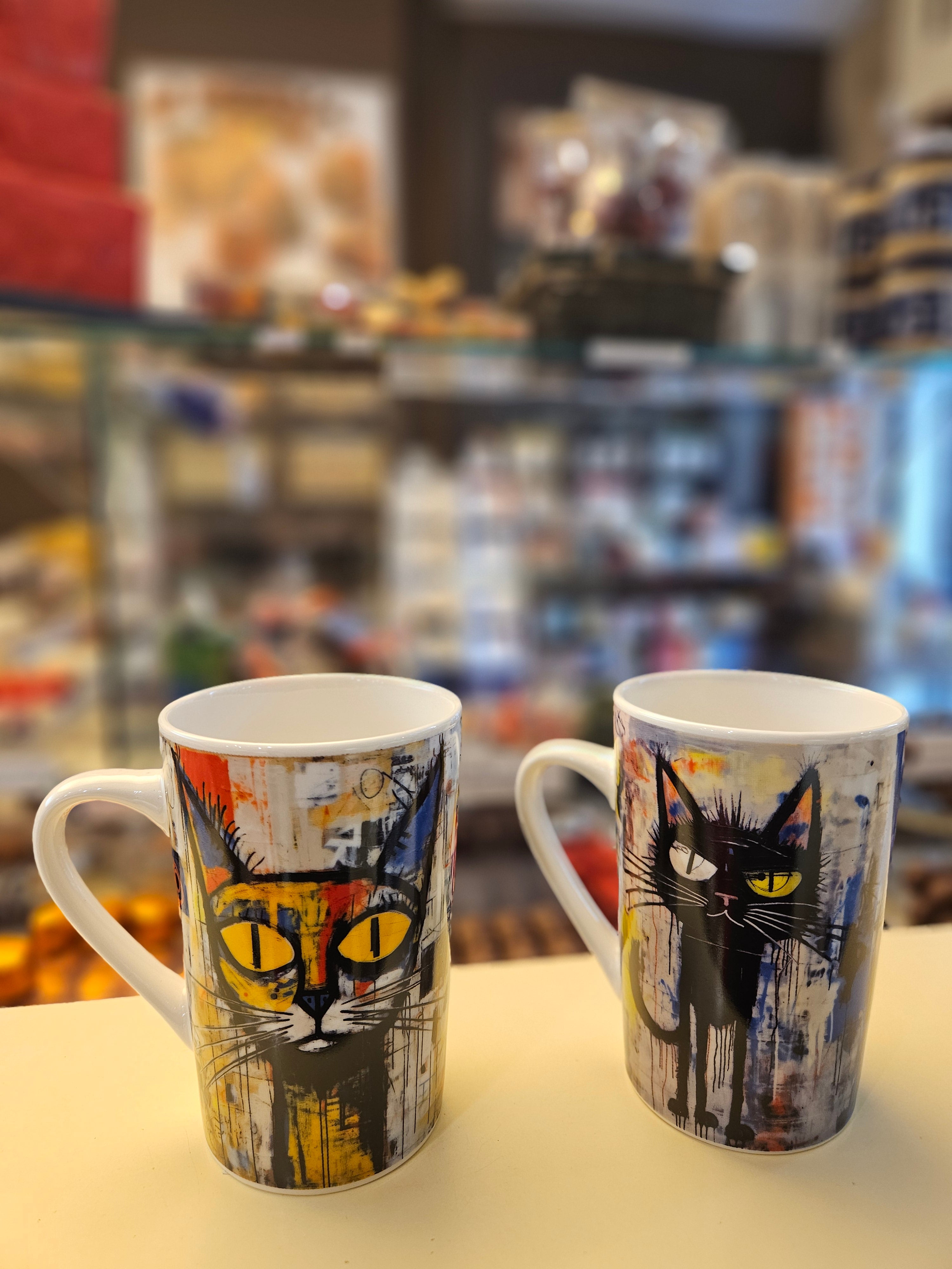 Taza blanca con ilustración de gato negro con luna y fondo de acuarelas naranjas y grises.