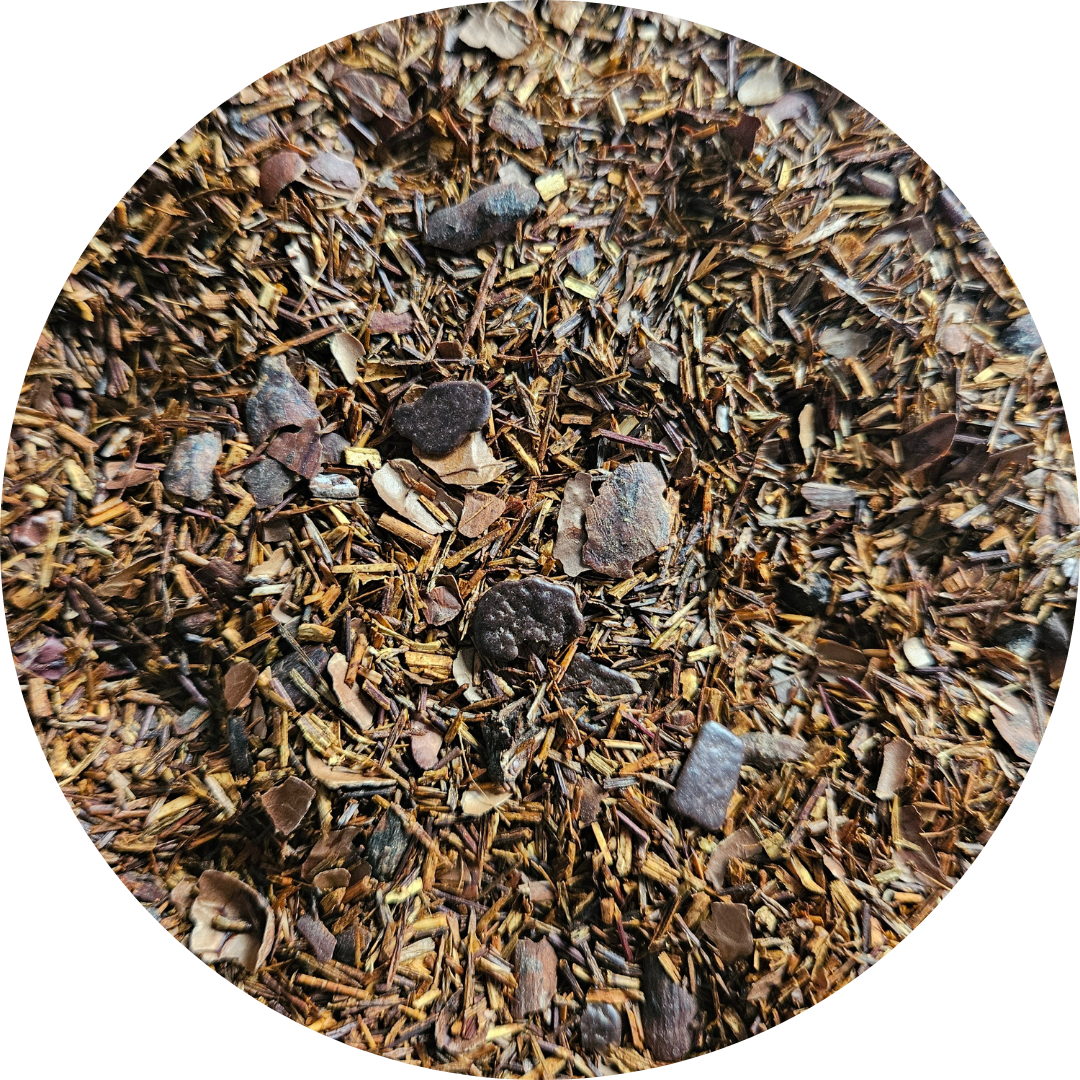 Mezcla de té rooibos con trozos de chocolate y caramelo visibles, textura suelta y color marrón rojizo.