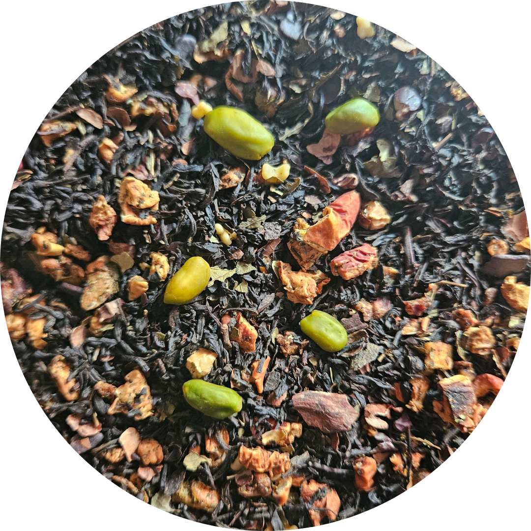 Mezcla de té negro con trozos de chocolate y pistachos verdes visible en primer plano.